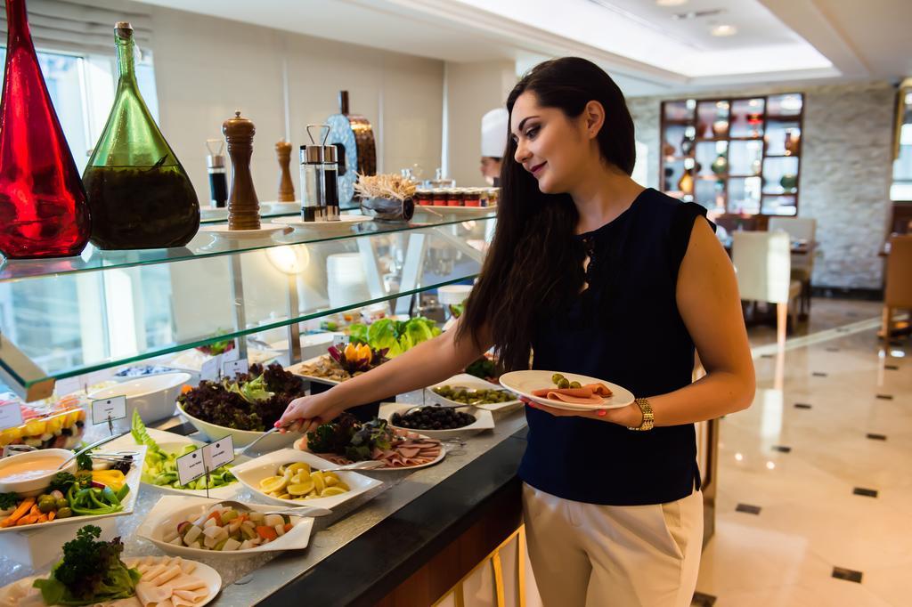 Grand Mercure Residencia Abu Dabi Exterior foto A woman selecting food from a buffet